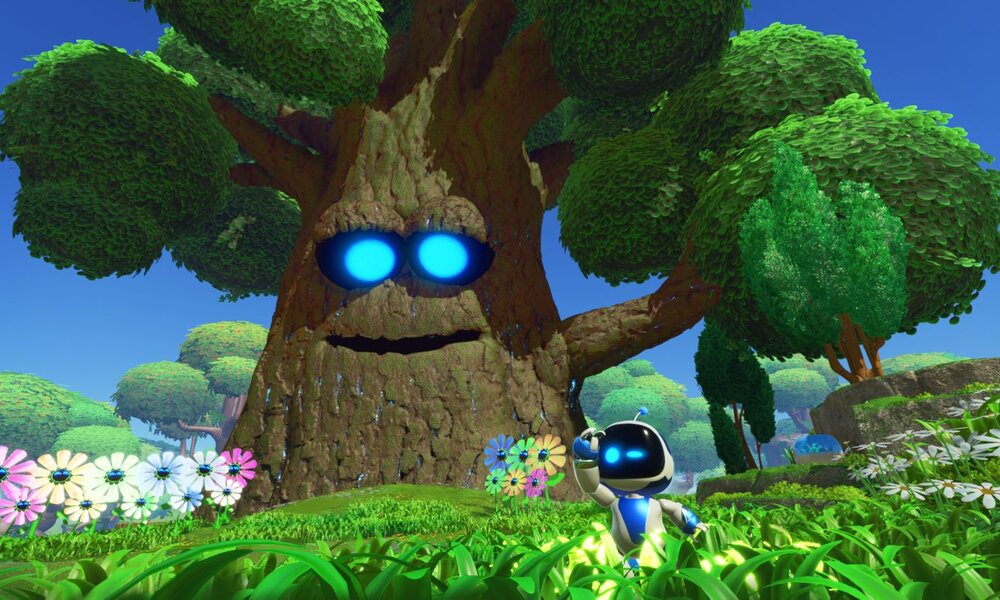 Ein kleiner Roboter mit leuchtend blauen Augen steht vor einem riesigen, sprechenden Baum mit leuchtenden Augen in einer blühenden Wiese. | © Sony Interactive Entertainment