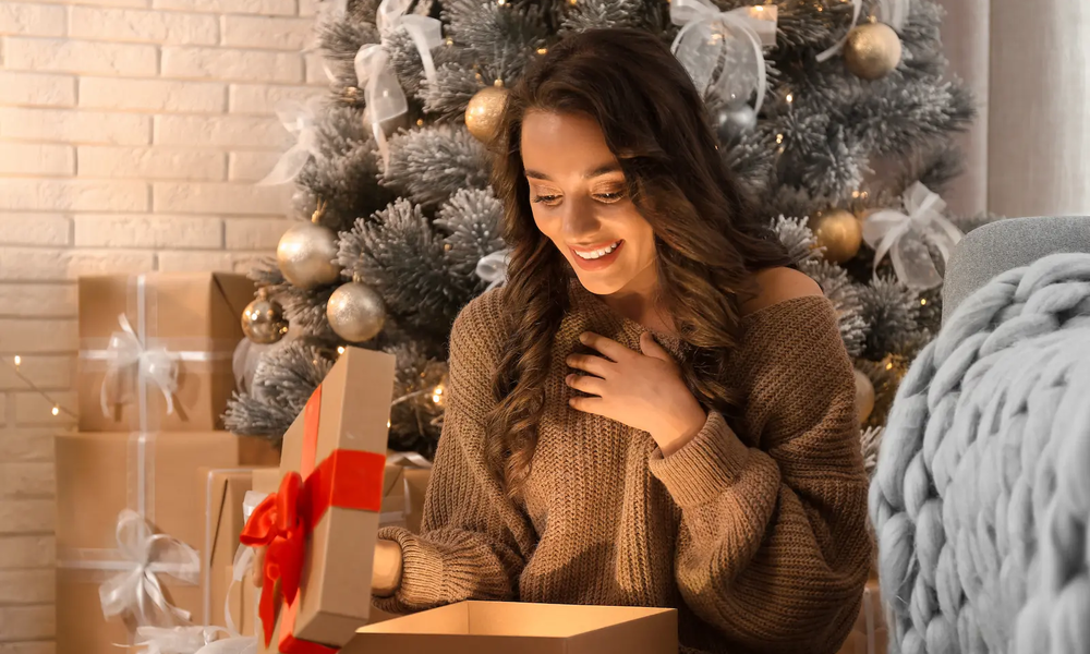 Frau öffnet Geschenk zu Weihnachten | © adobe.stock.com/New Africa