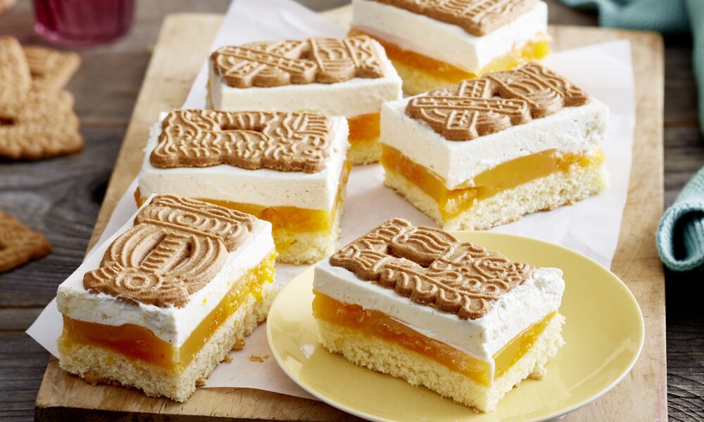 Mehrere Stück Mandarinen-Spekulatius-Kuchen auf einem Teller angerichtet, in weihnachtlicher Umgebung. | © 	Isabell Triemer