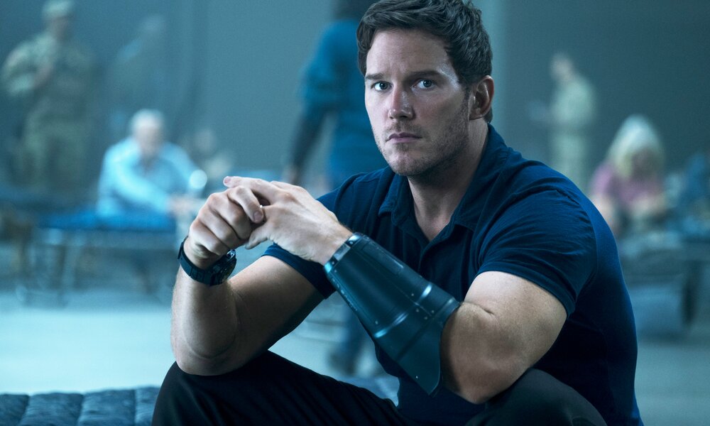 Chris Pratt sitzt mit ernstem Gesicht und kämpferischer Ausrüstung auf einer Liege in einer Szene aus dem Prime Video Film "The Tomorrow War" | © Prime Video