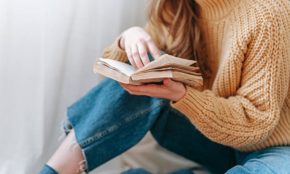 Frau hält Buch in den Händen | © Canva