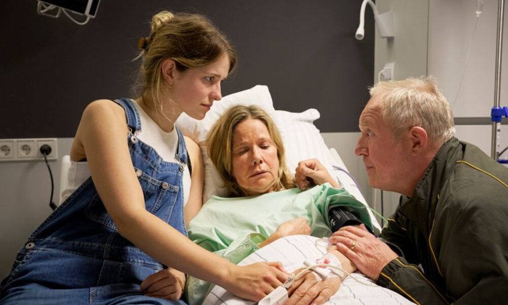 Mann greift sich an Brust, Frau sitzt daneben | © Getty Images / Milko