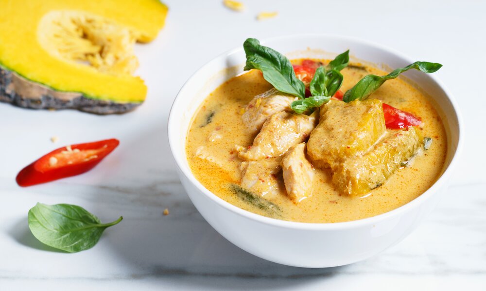 In einer weißen Schüssel Hähnchen-Kokos-Gericht angerichtet. | © Getty Images / 	SherSor