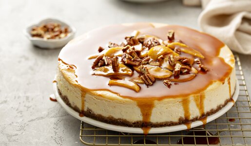 Apfel-Käsekuchen mit Karamelltopping und Nüssen dekoriert. | © Adobe Stock / fahrwasser