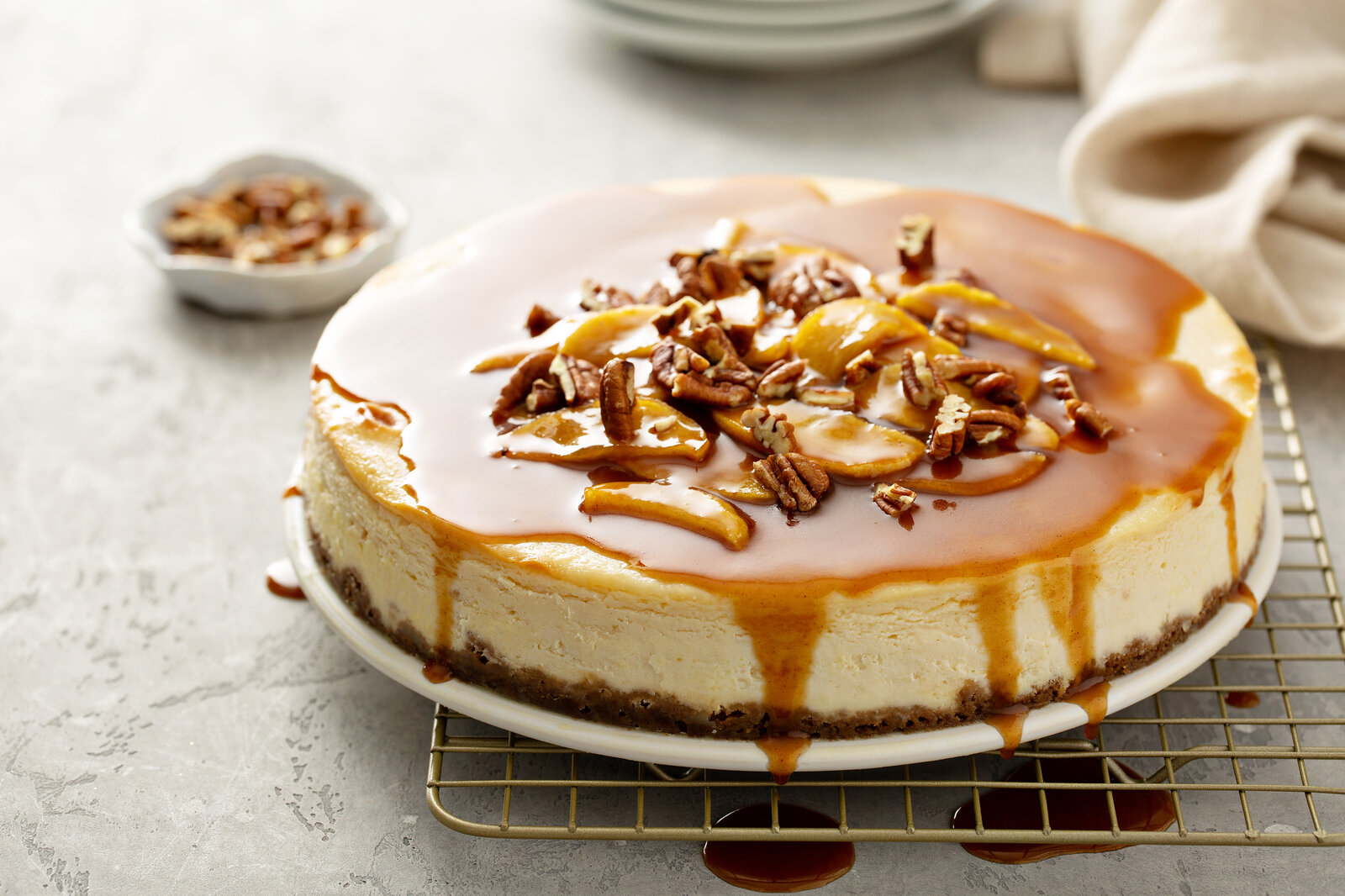 Apfel-Käsekuchen mit Karamelltopping und Nüssen dekoriert. | © Adobe Stock / fahrwasser