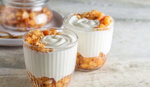 Apfel-Schichtdessert mit kleinen Apfelstücken abwechselnd geschichtet mit einer weißen Creme. | © Adobe Stock / Olga