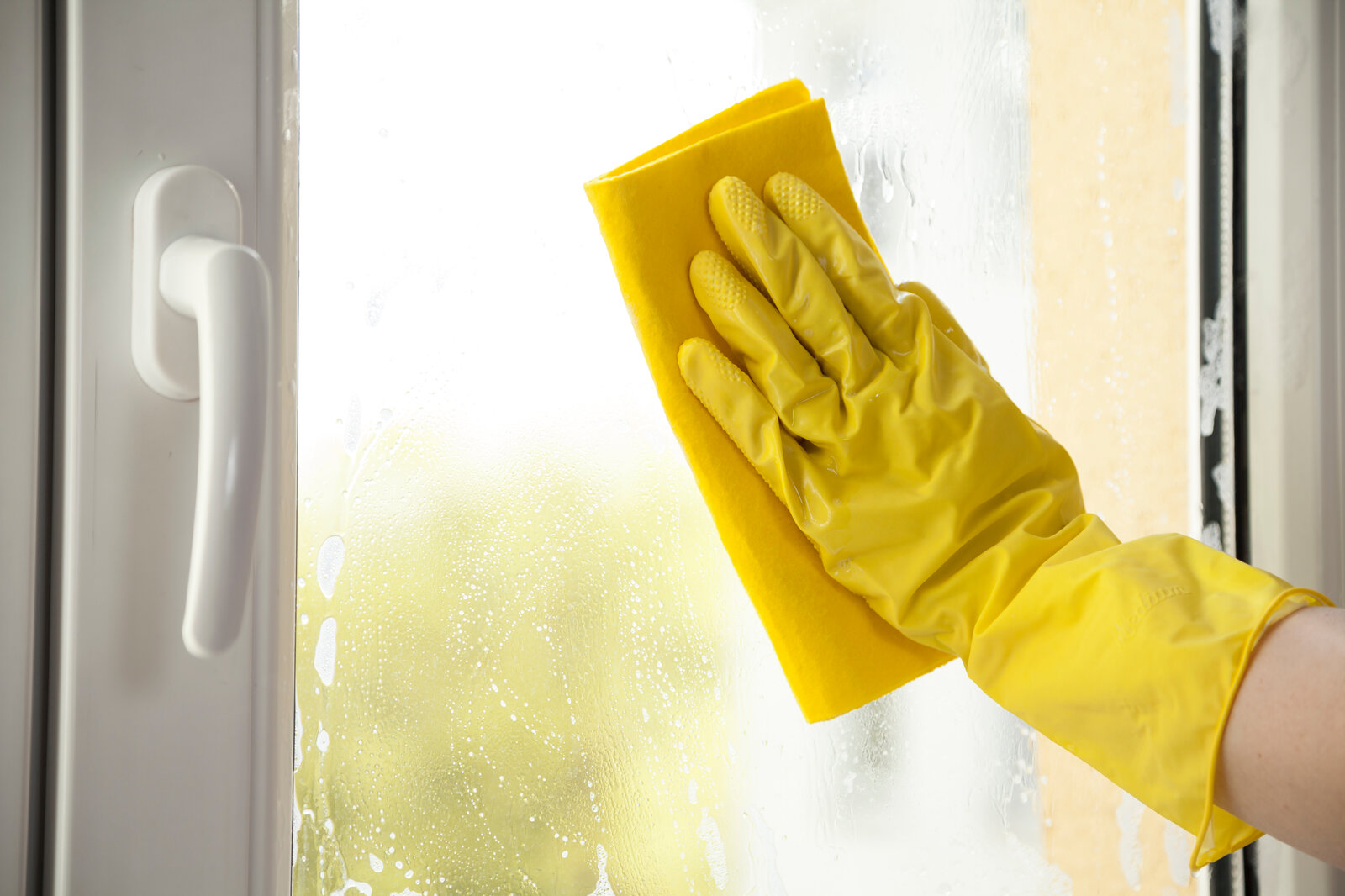 Eine Hand mit gelben Handschuh putzt ein Fenster  | © Adobe Stock/ Sp4764