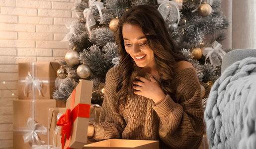 Frau öffnet Geschenk zu Weihnachten | © adobe.stock.com/New Africa