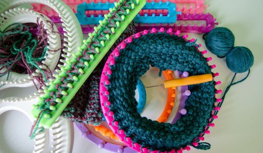 Bunte Strickringe, eine Stricknadel und zwei Wollknäuel in Blau und Grün liegen auf einem weißen Tisch. | © JMP Traveler / iStock / Getty Images Plus 