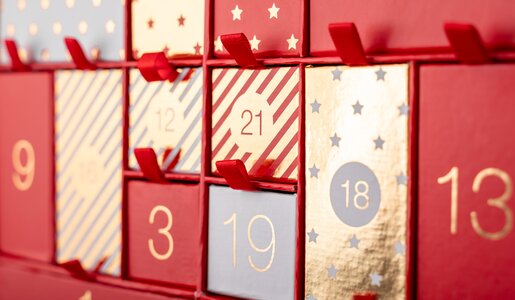 Nahaufnahme von einem roten Adventskalender mit verschiedenen nummerierten Türchen. | © Getty Images/karetoria