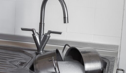 Eine silbernes Waschbecken in der Küche mit laufendem Wasser, in der Spüle liegen Töpfe in einem Schaumbad | © Adobe Stock/blende11.photo