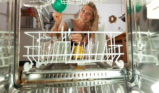 Spülmaschine von innen, am Ende der Spülmaschine sitzt ein blonde Frau, die gerade die Spülmaschine einräumt, in der Maschine sind einige Teller usw. | © Adobe Stock/Bernd Jürgens