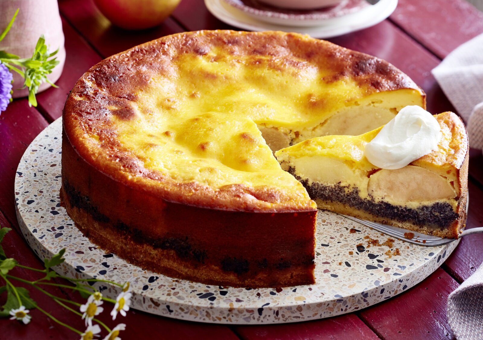 Angeschnittener Apfel-Schmandkuchen mit Mohnfüllung auf einem Kuchenteller. | © Isabell Triemer