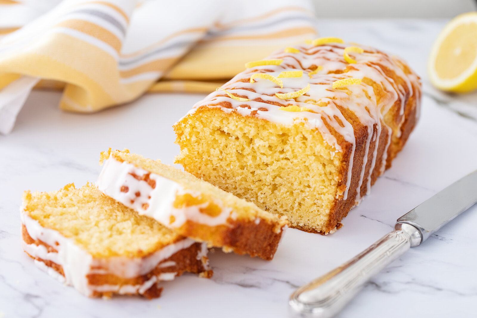 Angeschnittener Zitronenkuchen mit Zitronenkuss auf einem Kuchengitter. | © Getty Images / Cris Cantón