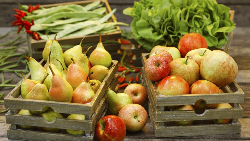 Körbe voll mit Birnen und Äpfeln, im Hintergrund Salat und Bohnen  | ©  Getty Images / poba