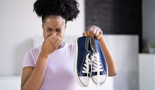 Frau hält sich die Nase zu und steckt Sneaker von sich weg  | ©  Getty Images / AndreyPopov