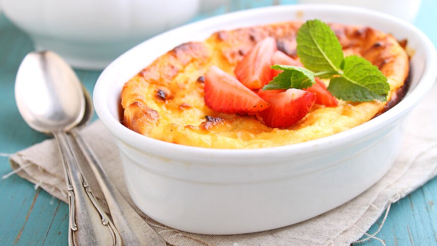 Auflaufform mit Quarkdessert, goldbraun, belegt mit frischen Beeren. | © Getty Images / alely