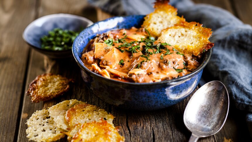 Deftige Suppe mit Parmesan-Cracker in Suppenschüssel. | © Getty Images / Westend61