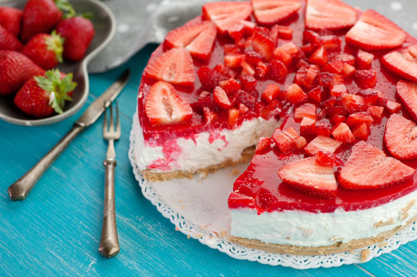 Erdbeer-Schmand-Kuchen in Nahaufnahme, aufgeschnitten und mit frischen Erdbeeren bestückt. | © Getty Images / 	tanialerro