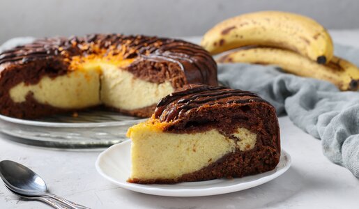 Angeschnittener Schoko-Bananenkuchen mit Quarkfüllung angerichtet auf einem Tortenboden. | © Getty Images /Angelika Mostova