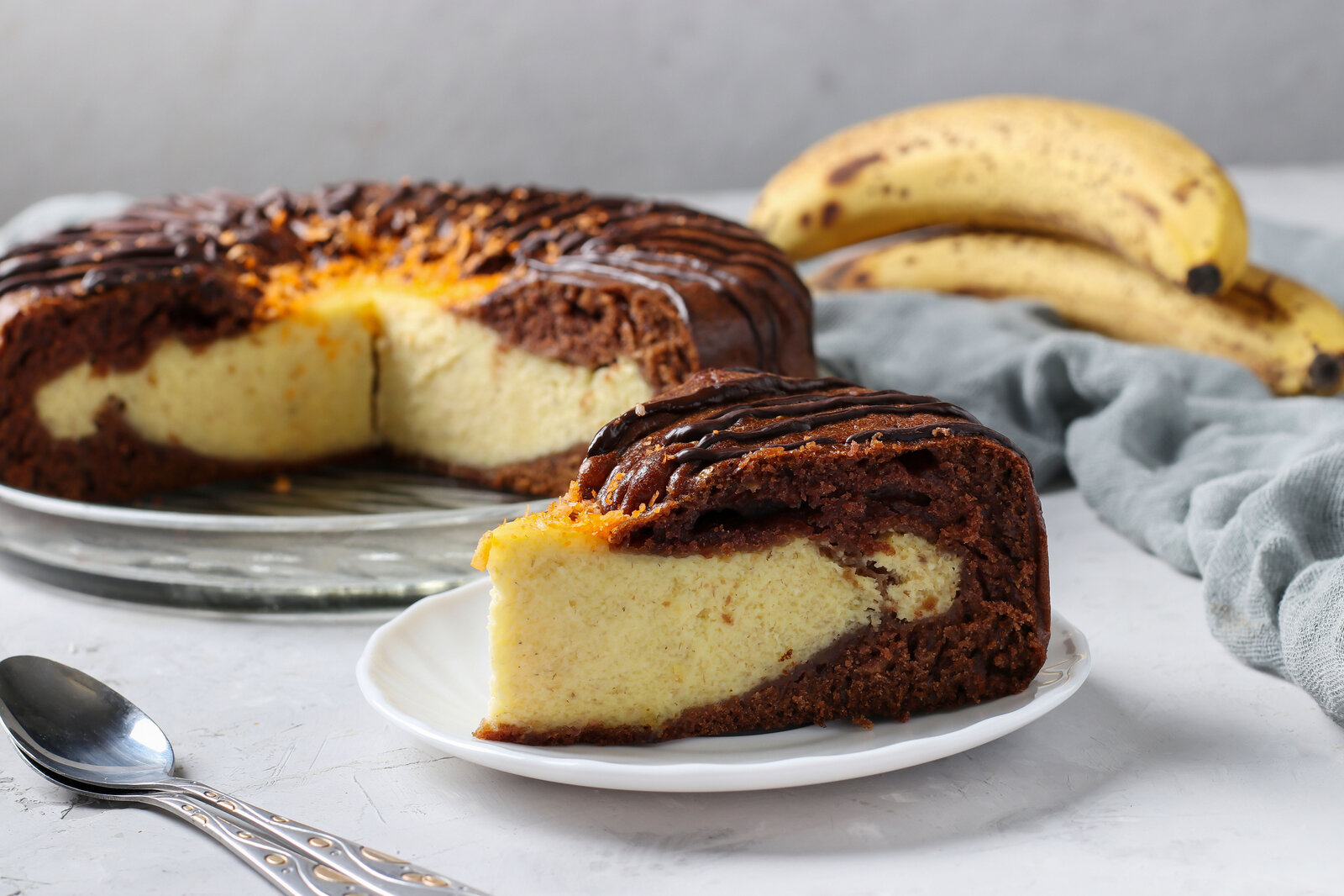 Angeschnittener Schoko-Bananenkuchen mit Quarkfüllung angerichtet auf einem Tortenboden. | © Getty Images /Angelika Mostova