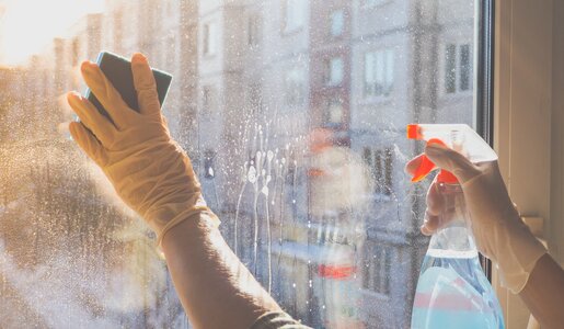 Hände in gelben Gummihandschuhen putzen mit Schwamm und Reinigungsmittel ein Fenster in der Morgensonne. | © Adobe Stock/ sablinstanislav
