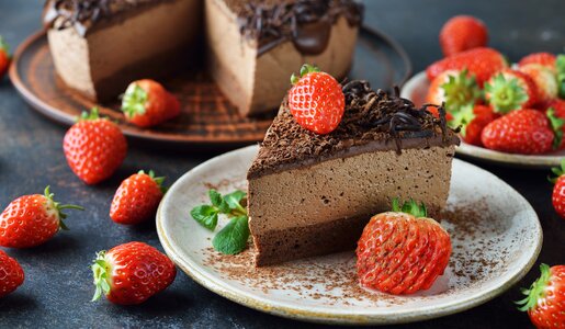 Angeschnittener Brownie-Käsekuchen auf Teller, Stück davon und frische Erdbeeren daneben. | © Getty Images / olvas