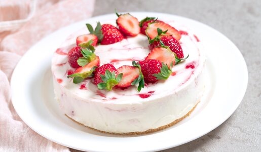 Erdbeer-Schmand-Torte ganz ohne Backen und Zucker angerichtet auf einem weißen Teller. | © Getty Images / yumehana
