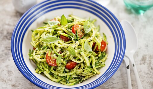 Zucchini-Salat in Pesto mit Cherry-Tomaten angerichtet auf blau-weißem Teller. | © Getty Images / 	Bartosz Luczak