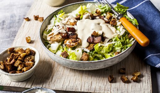 Caesar Salat mit Joghurt-Dressing in einer Schale angerichtet, darauf Croutons. | © Getty Images / 	Westend61