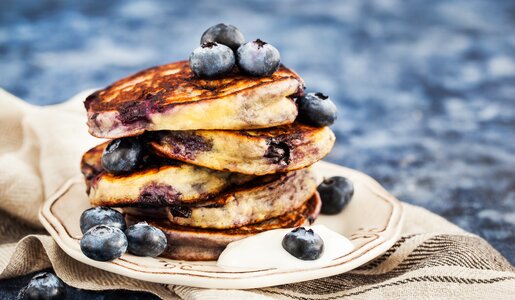 Fluffige Blaubeer-Pfannkuchen gestapelt auf einem Teller, der auf einem Leinentuch steht. | © Adobe Stock / kate_smirnova