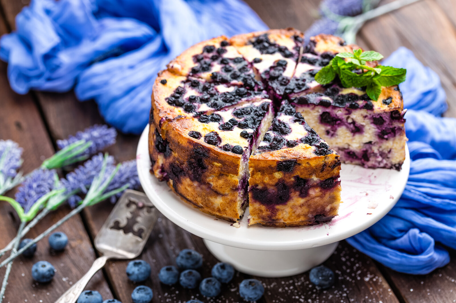 Angeschnittener Joghurtkuchen mit Blaubeeren daneben frischer Lavendel. | © Getty Images / YelenaYemchuk