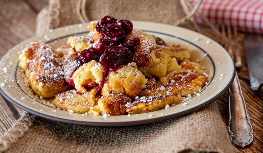 Fluffiger Kaiserschmarrn Low Carb ohne Zucker mit Puderzucker bestreut und mit heißen Kirschen garniert. | © Adobe Stock / Angelika Heine
