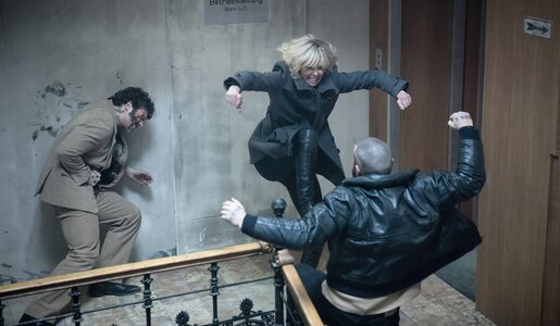 Blick in ein düsteres Treppenhaus in einer Szene aus dem Kinofilm "Atomic Blonde", in der Charlize Theron in heftigem Kampf gerade zwei Co-Darsteller besiegt. | © Imago Images/Capital Pictures
