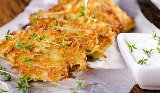 Aufgereihte Kohlrabipuffer auf einem weißen Teller angerichtet und mit Kräutern garniert. | © Getty Images / PopoudinaSvetlana