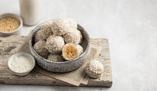 Viele kleine Kokos-Joghurt-Bällchen auf einem Teller angerichtet, einer davon aufgeschnitten. | © Adobe Stock / Anne DEL SOCORRO