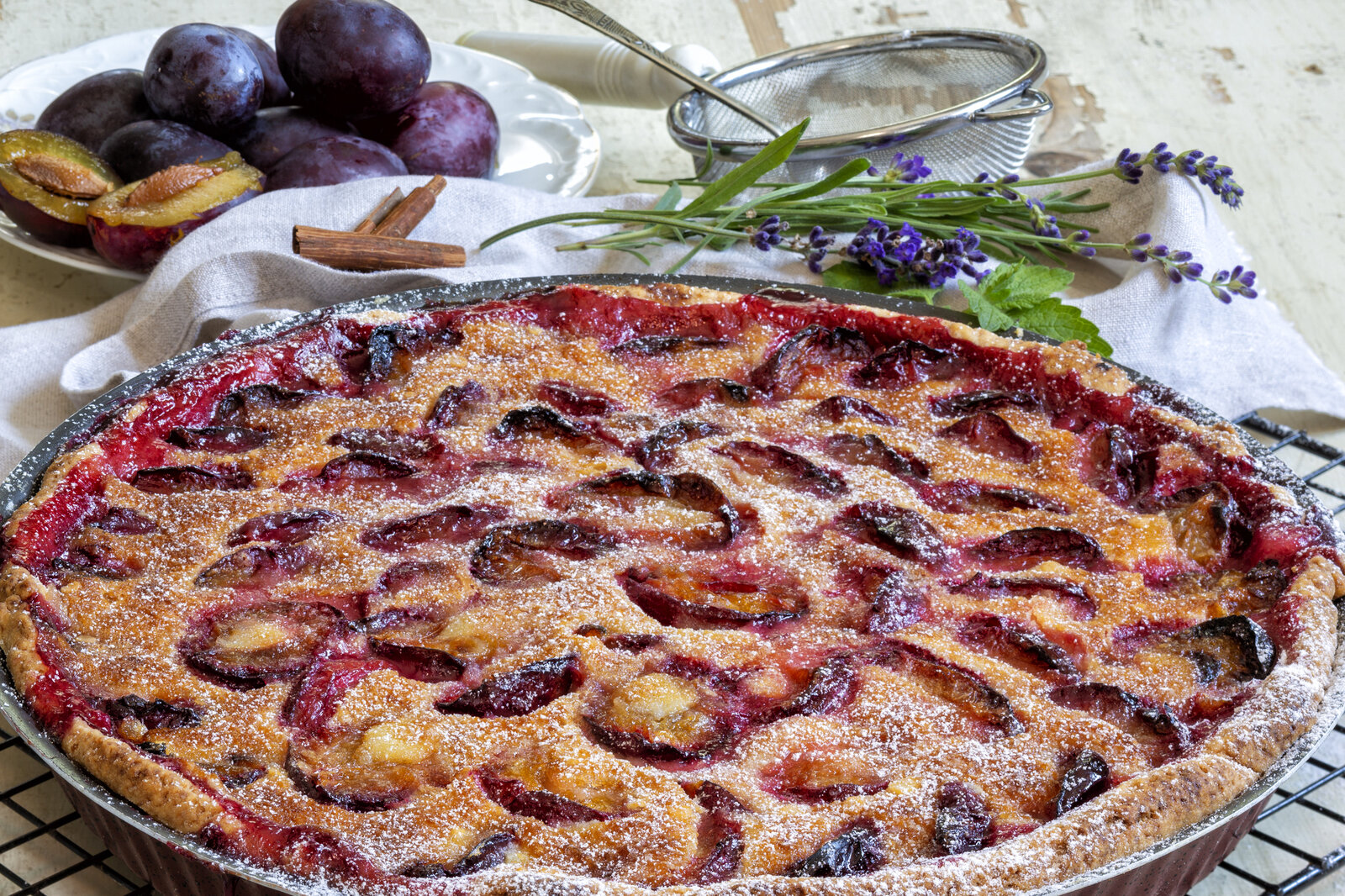 Pflaumenkuchen in Kuchenform, daneben frische Pflaumen und etwas frischer Lavendel. | © Getty Images / 	alle12