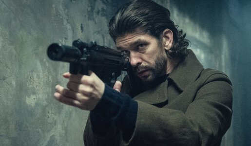 Ben Whishaw steht in Mantel und mit gezogener Waffe in einem düsteren Tunnel in einer Szene aus der Netflix-Serie "Black Doves". | © Netflix/Stefania Rosini