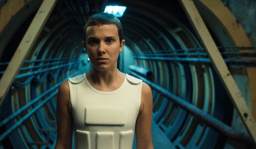 Millie Bobby Brown steht als Eleven in einer Szene der Netflix-Serie "Stranger Things" Staffel 4 in einem blau ausgeleuchteten Tunnel | © Netflix