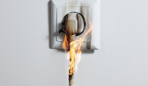 Ein brennender Stecker in der Steckdose | ©  Getty Images / AndreyPopov