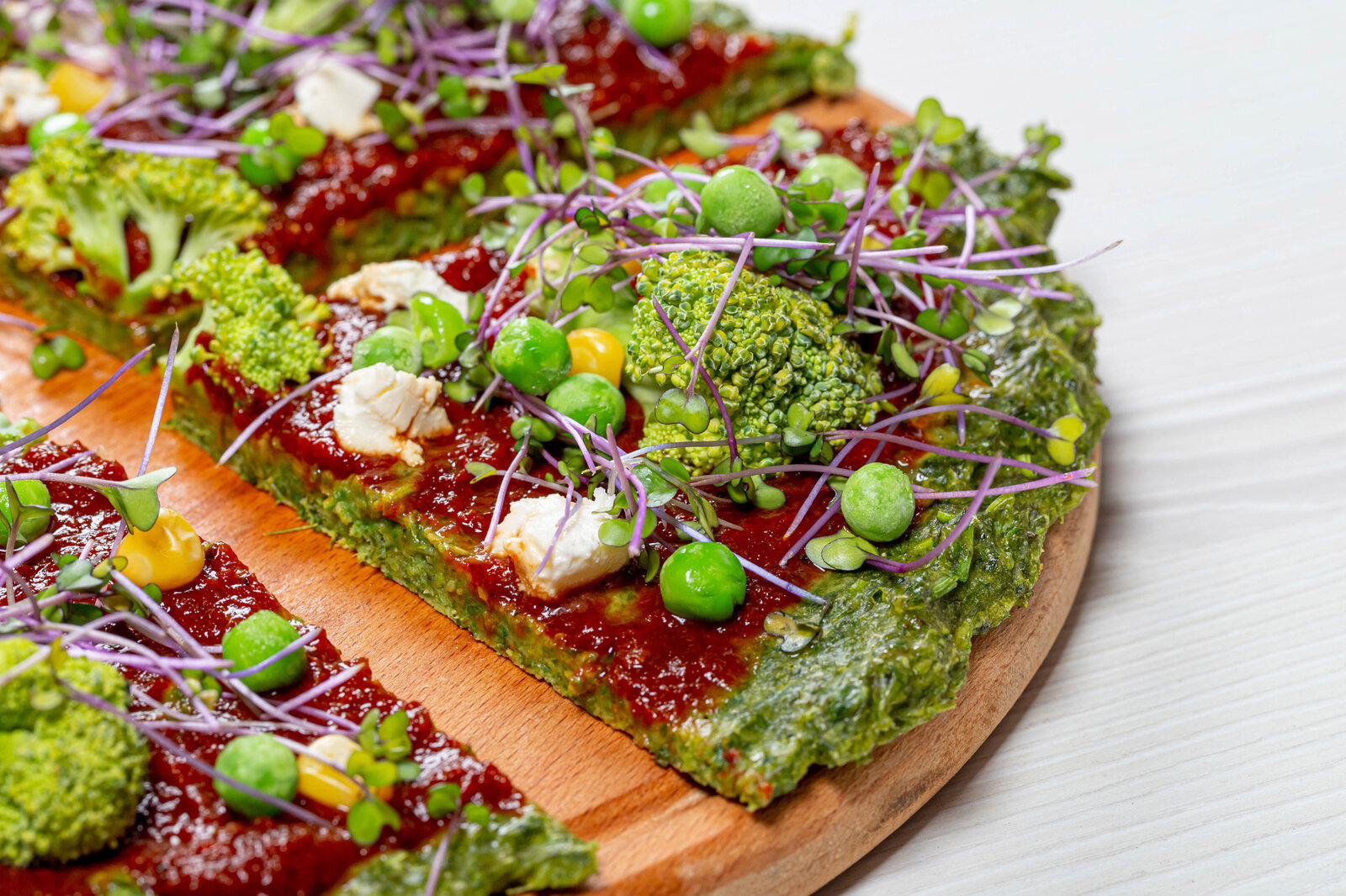 Grüne Pizza in Nahaufnahme, belegt mit Mozarella, Brokkoli und Erbsen. | © Getty Images / Anatolie Voiculet / 500px