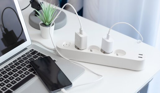 Schreibtisch mit Steckdosenleiste, Laptop und Handy | ©  Getty Images / simpson33