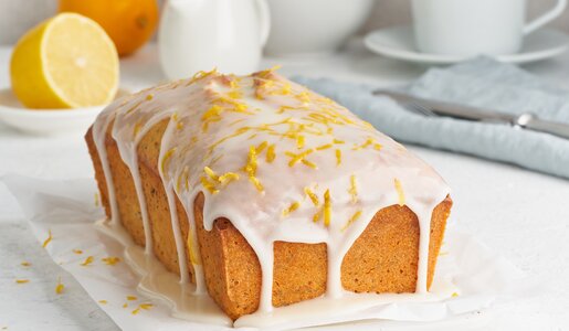Rechteckiger Zitronen-Joghurtkuchen mit Glasur und garnierten Zitronenzesten. | © Adobe Stock / Nata Bene