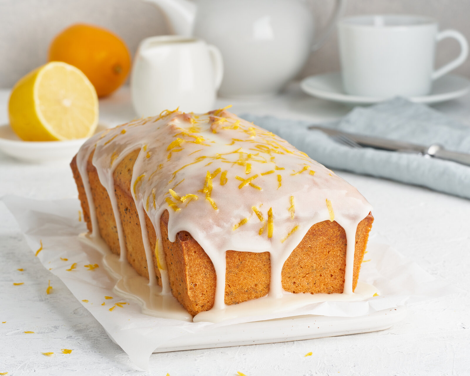 Rechteckiger Zitronen-Joghurtkuchen mit Glasur und garnierten Zitronenzesten. | © Adobe Stock / Nata Bene