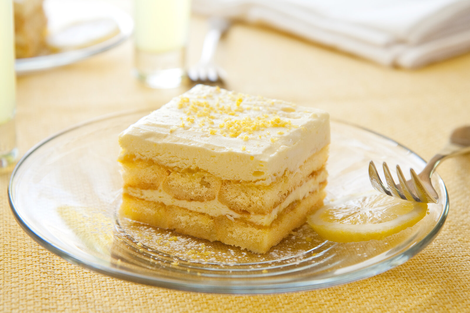 Ein Stück Zitronen-Tiramisu auf einem weißen Teller angerichtet, daneben eine Gabel. | © Getty Images / msheldrake