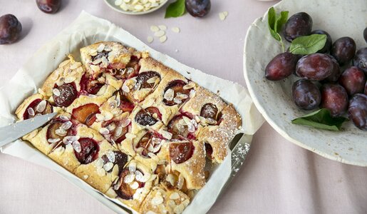 Pflaumenkuchen in Auflaufform neben frischen Pflaumen auf dem Teller. | © Getty Images / ©Tasty food and photography