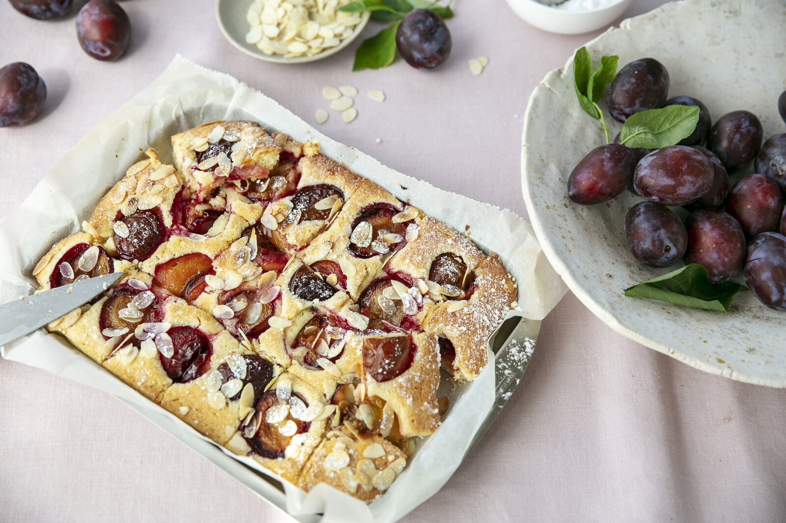 Pflaumenkuchen in Auflaufform neben frischen Pflaumen auf dem Teller. | © Getty Images / ©Tasty food and photography