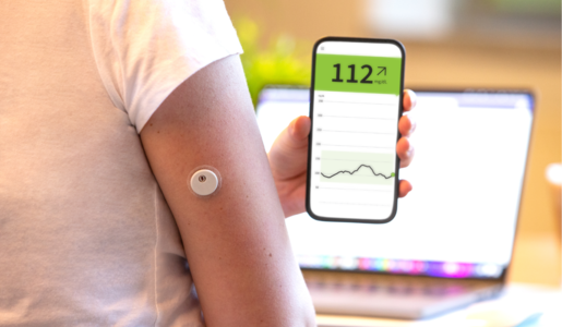 Person mit weißem T-Shirt trägt einen Glukosesensor am Oberarm und liest den Blutzuckerspiegel auf einem Smartphone ab. | © Rothenburg & Partner