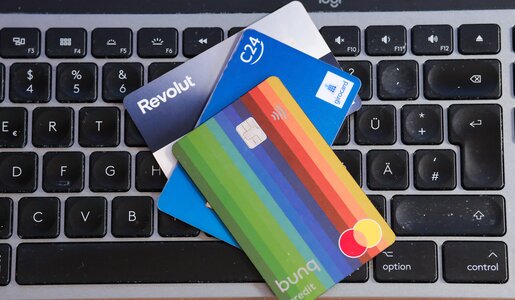 Drei verschiedene Kreditkarten, darunter eine bunte Mastercard, liegen auf einer schwarzen Computertastatur mit deutschen Buchstaben. | © IMAGO/Michael Gstettenbauer