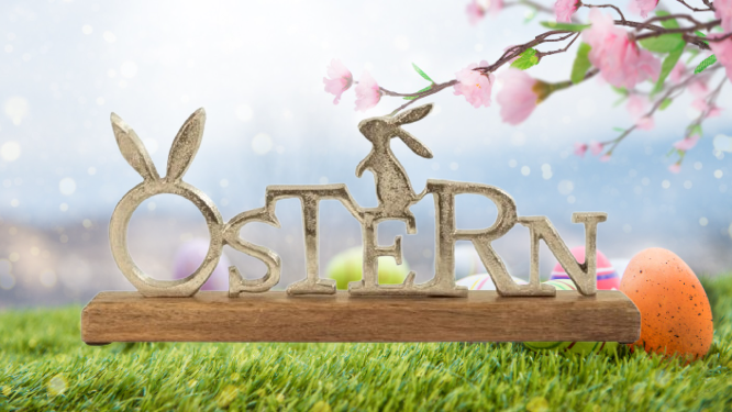 Aufsteller mit dem Schriftzug Ostern vor österlichem Hintergrund | © Amazon/Getty/loops7 
